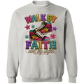 An ash color crewneck sweatshirt featuring a colorful graphic print with the text 'WALK BY FAITH not by sight' and an illustration of pink and purple high-top sneakers decorated with stars.