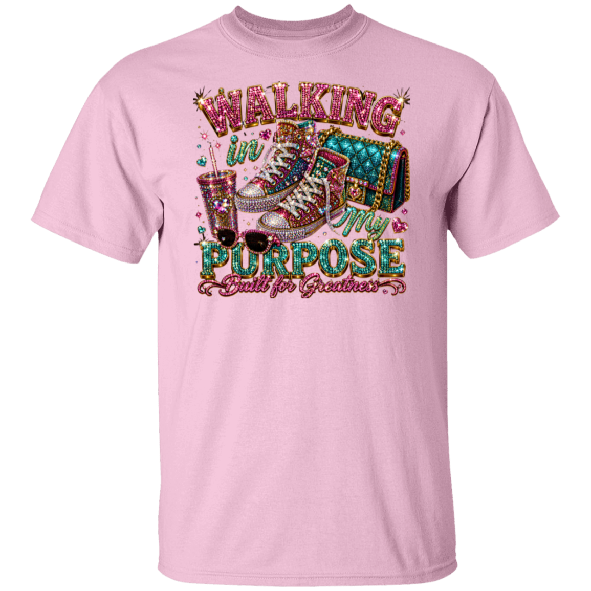 A light pink short-sleeve crewneck t-shirt featuring a large, colorful graphic on the front. The graphic displays a pair of embellished high-top sneakers, a drink with straws, and the text 'WALKING IN MY PURPOSE Built for Graduation' in a glittery, decorative font.
