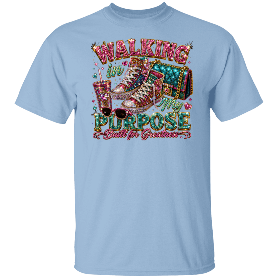 A light blue crewneck t-shirt featuring a large, colorful graphic print on the front. The graphic depicts a pair of glittery high-top sneakers, a drink with straws, sunglasses, and the text 'WALKING IN MY PURPOSE Built for Graduates' in a decorative, marquee-style font.